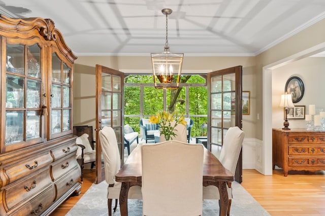 dining space with a chandelier, ornamental molding, and light hardwood / wood-style flooring