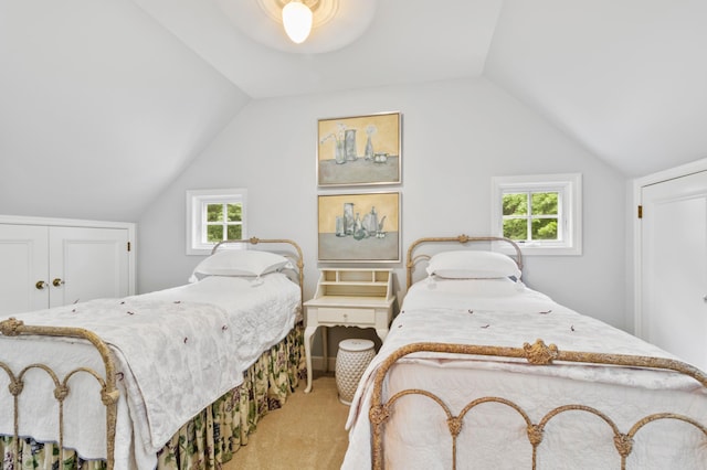 bedroom with lofted ceiling, light colored carpet, and a closet