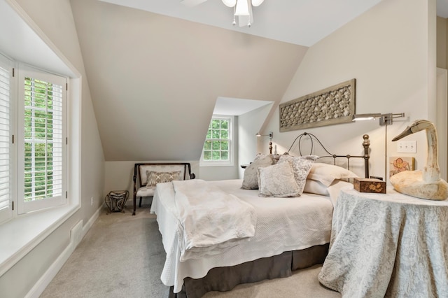 carpeted bedroom with ceiling fan, multiple windows, and lofted ceiling