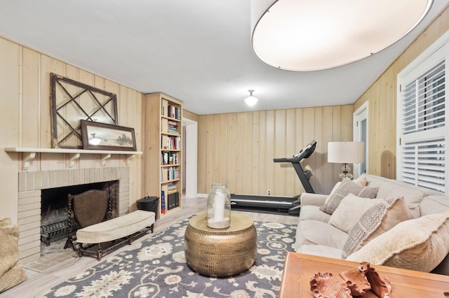 living room featuring light wood-type flooring, a fireplace, and wood walls