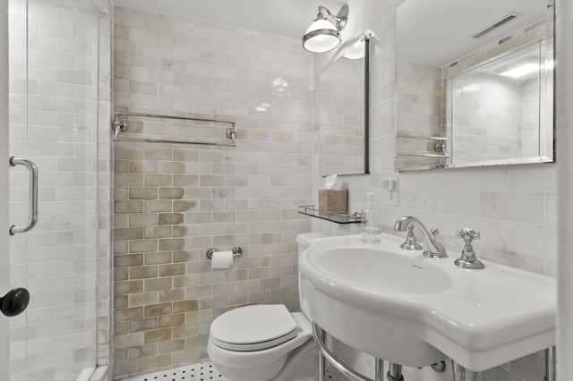 bathroom featuring a shower with door, decorative backsplash, sink, tile walls, and toilet