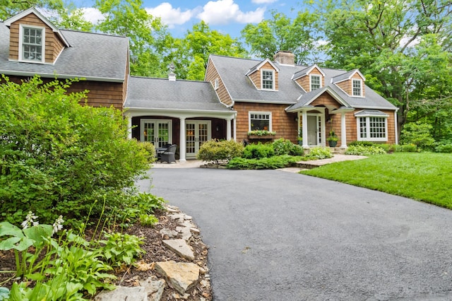 cape cod house with a front lawn and french doors