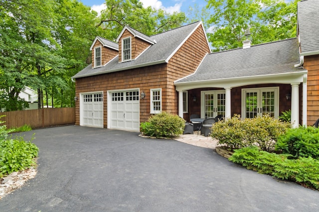 cape cod house featuring a garage, a patio area, and french doors