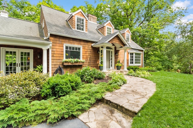 cape cod home featuring a front yard and french doors