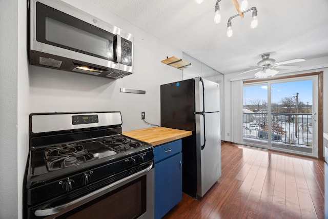 kitchen featuring butcher block counters, stainless steel appliances, dark hardwood / wood-style floors, ceiling fan, and blue cabinets