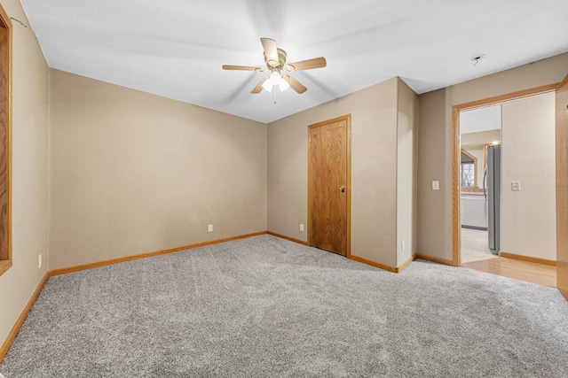 unfurnished bedroom featuring ceiling fan, light colored carpet, and stainless steel refrigerator