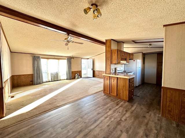 kitchen featuring kitchen peninsula, wooden walls, white appliances, dark wood-type flooring, and beamed ceiling