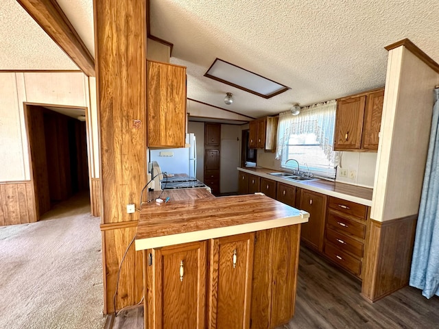 kitchen featuring a textured ceiling, wooden walls, sink, vaulted ceiling, and butcher block countertops