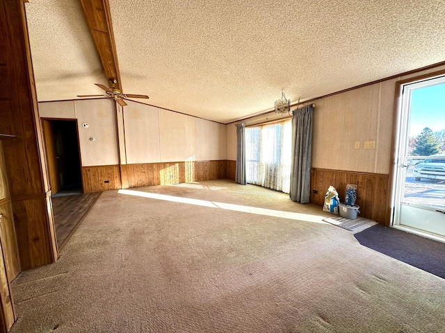 empty room with ceiling fan, a textured ceiling, light carpet, and beamed ceiling