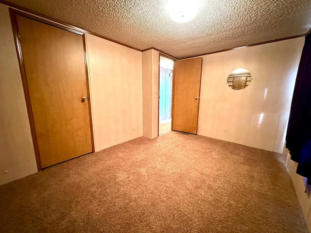 spare room with carpet floors, a textured ceiling, and wood walls