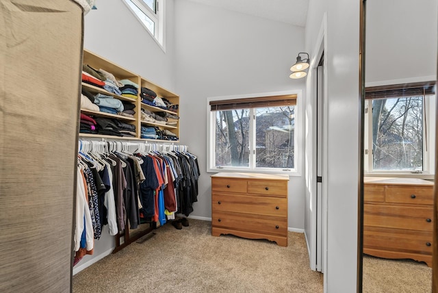 spacious closet with light colored carpet and a high ceiling