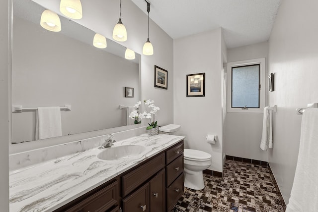 bathroom featuring toilet, vanity, and baseboards