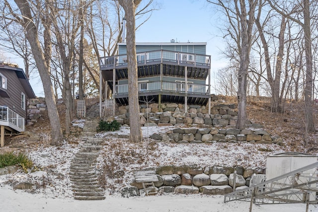 snow covered rear of property featuring stairway