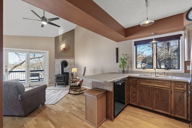 kitchen featuring open floor plan, black dishwasher, vaulted ceiling, a peninsula, and a sink