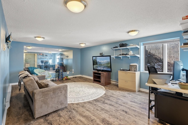 living room with baseboard heating, a textured ceiling, baseboards, and wood finished floors