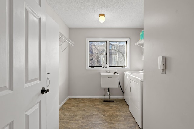 washroom with washing machine and clothes dryer, laundry area, a textured ceiling, and baseboards