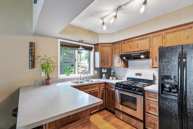 16164 Lakeside Ave SE, Prior Lake, MN 55372 - kitchen with black fridge, stainless steel range with gas stovetop, under cabinet range hood, a sink, and a peninsula