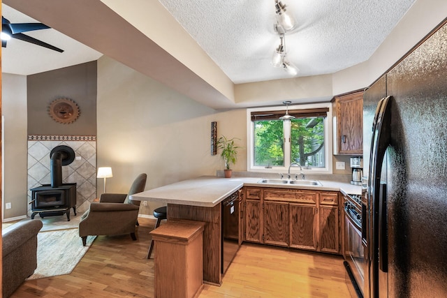 16164 Lakeside Ave SE, Prior Lake, MN 55372 - kitchen featuring black appliances, a sink, a peninsula, light wood finished floors, and a textured ceiling
