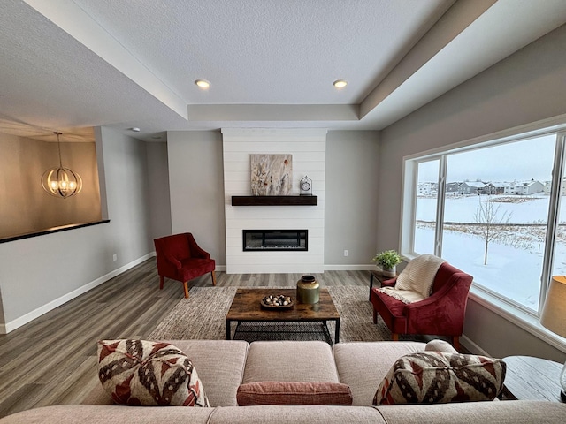 living room with hardwood / wood-style flooring, an inviting chandelier, a water view, a fireplace, and a textured ceiling