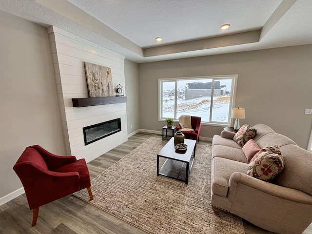 living room featuring a large fireplace, hardwood / wood-style floors, and a textured ceiling