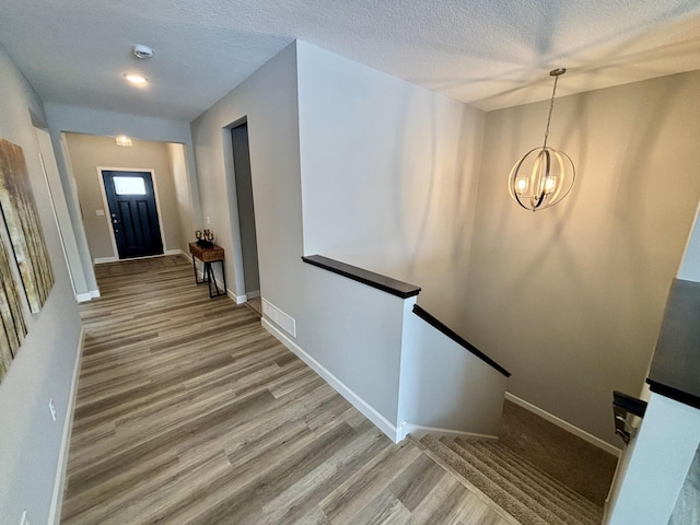 stairs with hardwood / wood-style floors, a textured ceiling, and a chandelier