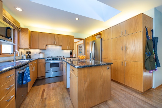 kitchen featuring light wood-type flooring, stainless steel appliances, sink, and a center island