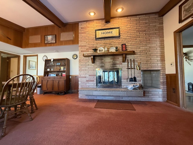 carpeted living room featuring a fireplace, beam ceiling, and wood walls