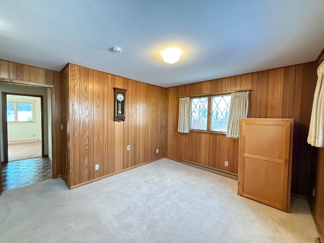 carpeted spare room with a baseboard radiator and wooden walls