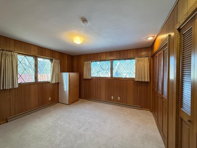 unfurnished room featuring a baseboard radiator, plenty of natural light, and light carpet