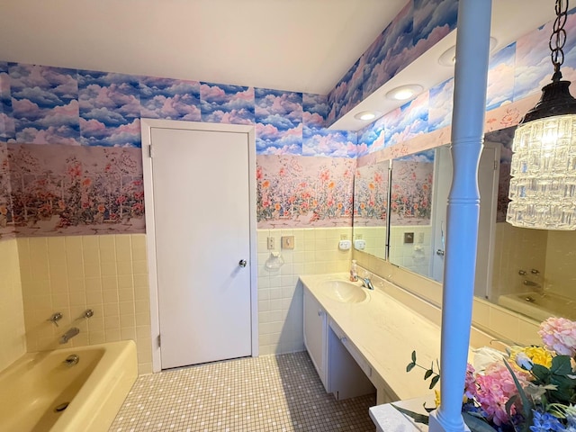 bathroom with a washtub, vanity, tile patterned floors, and tile walls