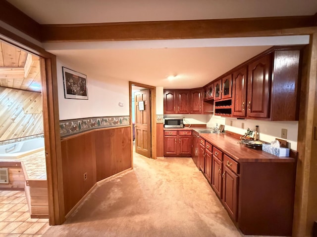 kitchen featuring wood counters, wood walls, sink, light carpet, and beam ceiling