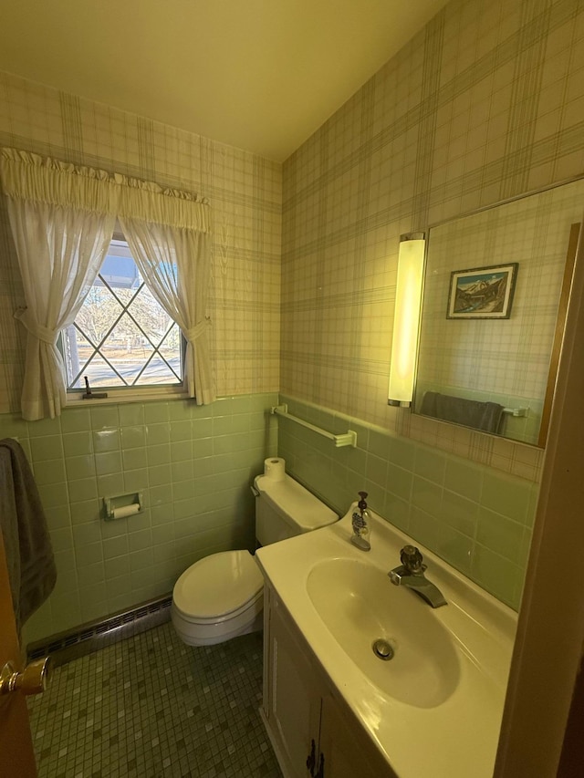 bathroom featuring toilet, tile walls, baseboard heating, vanity, and tile patterned flooring