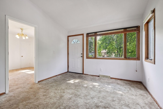 carpeted entryway with lofted ceiling and a chandelier