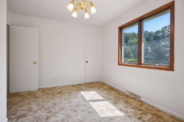 carpeted spare room featuring a notable chandelier