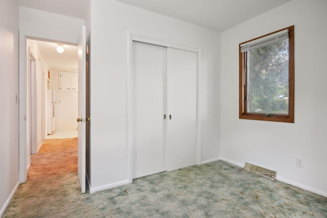 unfurnished bedroom with light colored carpet, multiple windows, and a closet