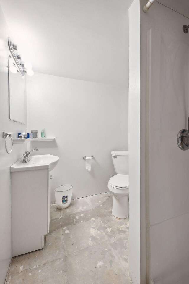 bathroom with toilet, vanity, and concrete flooring