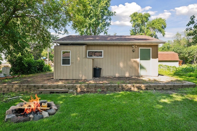 view of outdoor structure with an outdoor fire pit and a lawn