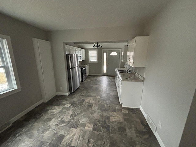 kitchen featuring sink, white cabinetry, stainless steel appliances, and a chandelier