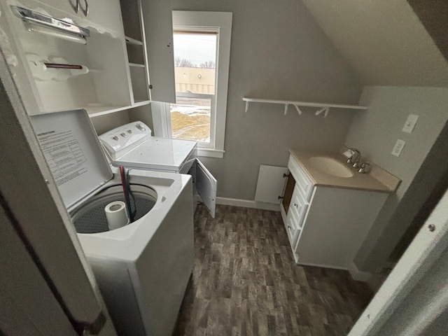 laundry area featuring dark wood-type flooring, washing machine and clothes dryer, and sink