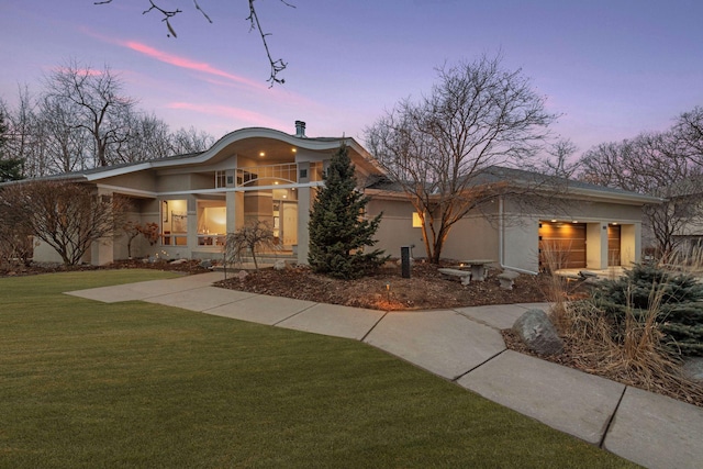 mid-century inspired home with stucco siding, driveway, and a yard