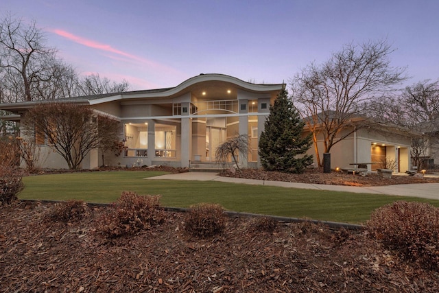 rear view of property with a lawn and stucco siding