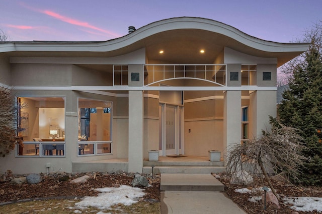 view of front of home with stucco siding and a balcony