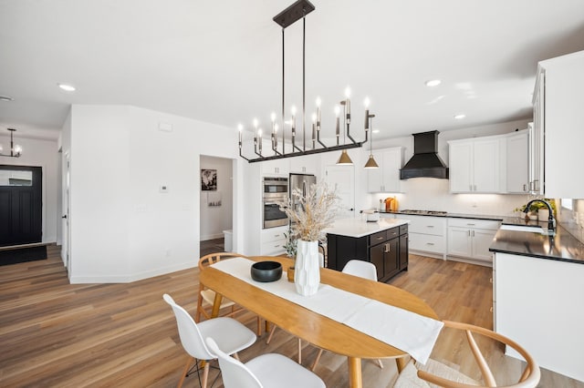 kitchen featuring decorative light fixtures, a center island, sink, white cabinetry, and custom range hood