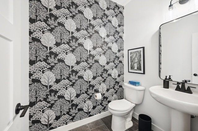 bathroom with toilet, sink, and tile patterned floors