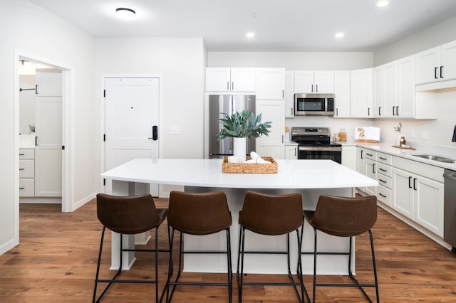 kitchen with white cabinetry, stainless steel appliances, dark hardwood / wood-style flooring, and a kitchen island