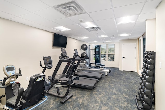 exercise room featuring dark colored carpet and a drop ceiling