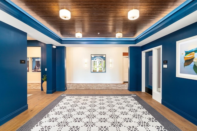 hall with wooden ceiling, light hardwood / wood-style floors, and a raised ceiling