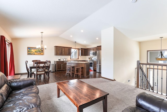 living room featuring dark hardwood / wood-style floors, a notable chandelier, and vaulted ceiling