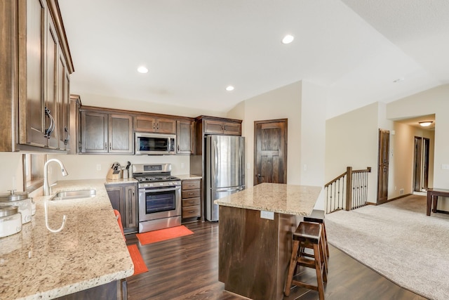 kitchen with vaulted ceiling, sink, appliances with stainless steel finishes, and a kitchen island