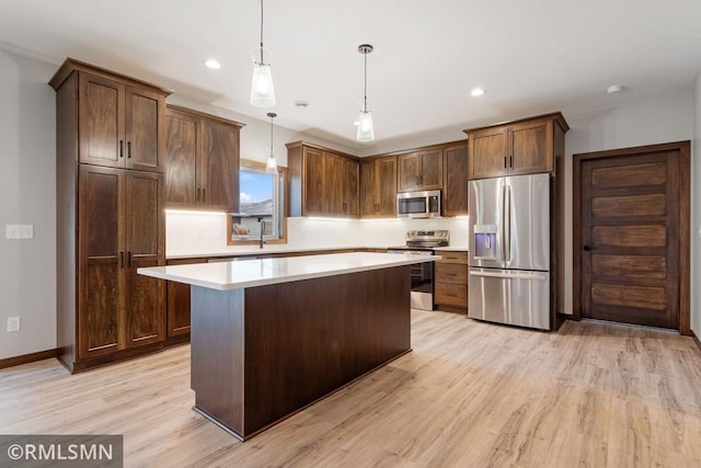 kitchen featuring stainless steel appliances, decorative light fixtures, dark brown cabinets, light hardwood / wood-style flooring, and a center island